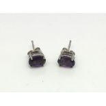 A pair of amethyst ear studs set in silver.