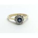 An 18ct gold ring set with a central sapphire and surrounded by eight diamonds in a flowerhead