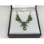 A boxed necklace set with peridot, seed pearls and