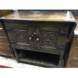 A carved oak cupboard the top with a drop flap abo