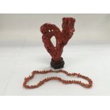 Two items of coral comrades a necklace and a carve