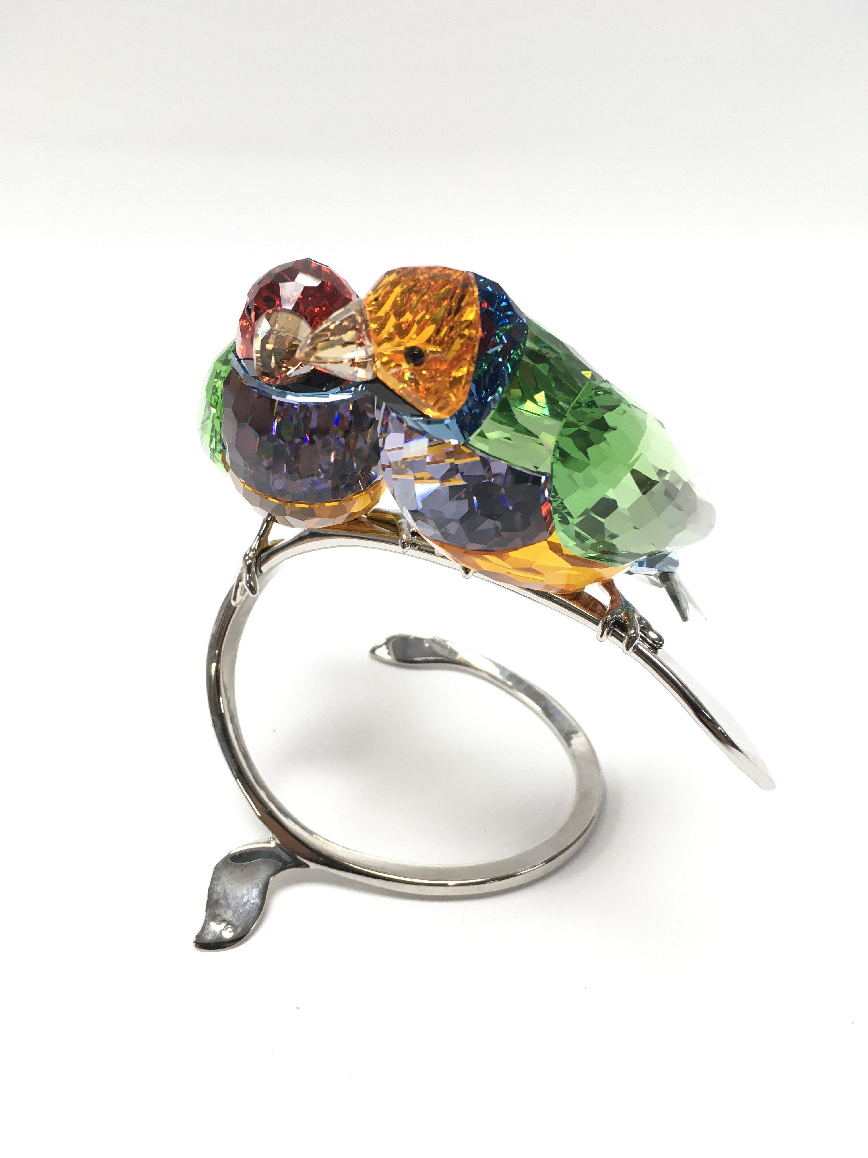 A Swarovski pair of Gouldian Finches perched on a