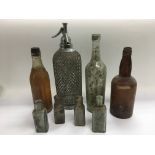 A collection of old bottles including a soda sypho