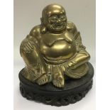 A brass figure of a buddha on a carved hardwood st