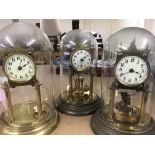 Three anniversary clocks under glass domes