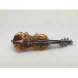 A silver and amber brooch in the form of a violin,