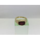 An unmarked gold ring with a red stone, approx 1.6