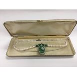 A cultured pearl necklace set with green stones an