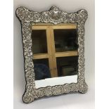 A silver framed mirror with repousse work decorati