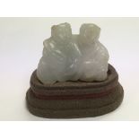 A small jade carving of two figures on a stand (no