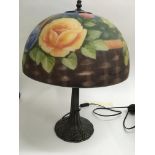 A glass side lamp the shade decorated with flowers and foliage.