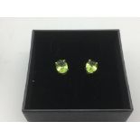 A boxed pair of silver studs set with peridots.