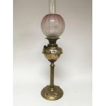 A brass oil lamp with an acid etched glass shade t