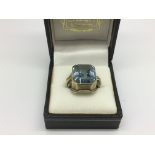 A gold ring set with a large aquamarine stone, app