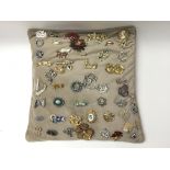 A collection of approximately 50 brooches presented on a cushion