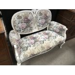 A white painted Edwardian two seater sofa covered in floral upholstery on Cabriole legs.