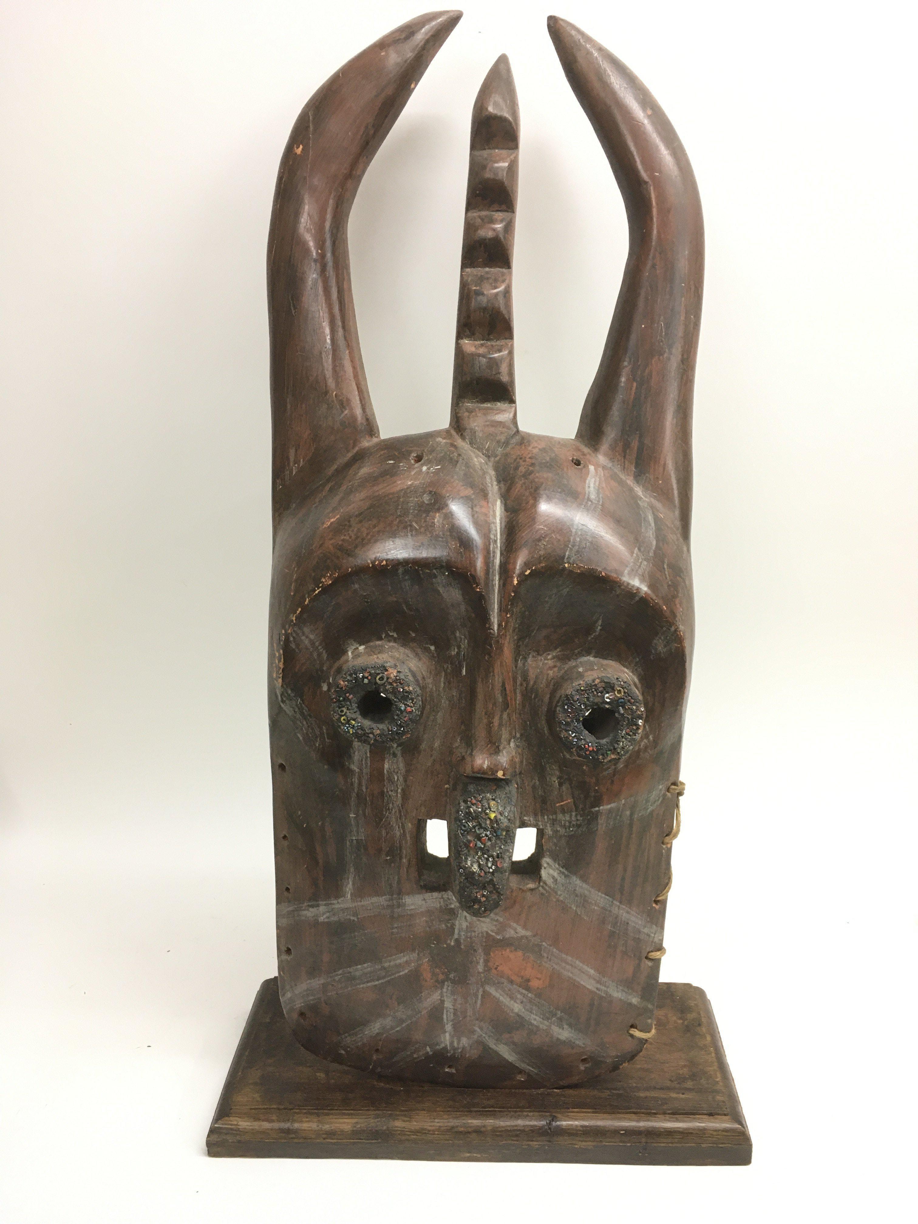 A large wooden tribal mask inset with glass trader