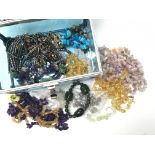 A box containing a collection of natural stone jewellery including necklaces and bracelets, some