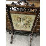 A Victorian walnut fire screen inset with tapestry panel flanked by barley Twist columns on cabriole