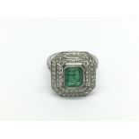 A platinum ring set with a large emerald cut central emerald and surrounded by two octagonal halos