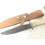 A Bowie knife with a polished bone handle With a Damascus steel blade.