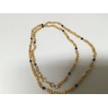 A High grade gold necklace set with alternating patterned links and small sapphire. Total weight