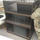 A simulated rosewood three section bookcase with glass sliding doors.