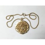 A gold coloured pendant in the style of Medusa, by Sphinx, with chain