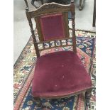 An Edwardian oak nursing chair with an upholstered back and seat and turned supports.