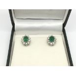 A boxed pair of emerald and diamond cluster ear studs. The oval cut emeralds approx 1.90ct and RBC