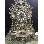 A brass mantel clock of classical form with side candelabra.