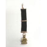 A seal fob suspended on a ribbon set with 9ct gold.