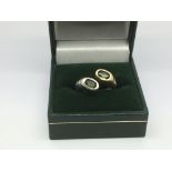 A modern design ring set with two green stones and small diamonds, approx 6.9g and approx size K.