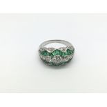 A platinum, emerald and diamond dress ring set with three graduated old cut diamonds, calibre cut