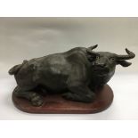 A spelter figure of a recumbent buffalo raised on a wooden base, approx length 43cm.