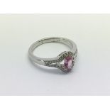 An 18ct white gold ring set with an oval cut pink sapphire and diamond ring with split diamond