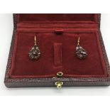 A boxed pair of flower design drop earrings set with garnets and diamonds.