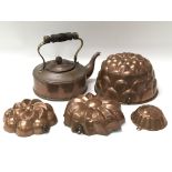 A Victorian copper kettle together with four copper jelly moulds of various sizes and designs