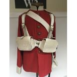A quality replica 19th century red tunic with white leather webbing and back pack. On a metal