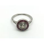 A platinum target style ruby and diamond ring set with a central old cut diamond, approx 0.50ct,
