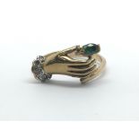 A 9ct yellow gold ring in the style of a hand holding an emerald with diamond cuff, ring size approx