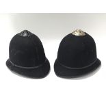 Two small police helmets with liners and chin straps but no badges
