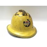 A vintage cork fireman’s helmet in painted yellow and printed emblem