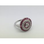 A platinum, ruby and diamond dress ring set with a central old cut diamond, a halo of rubies, a halo