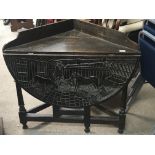 A carved oak drop leaf table the top carved with a