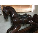 A large carved wooden rocking horse with leather saddle and bridal. 160 cm by 160 cm .