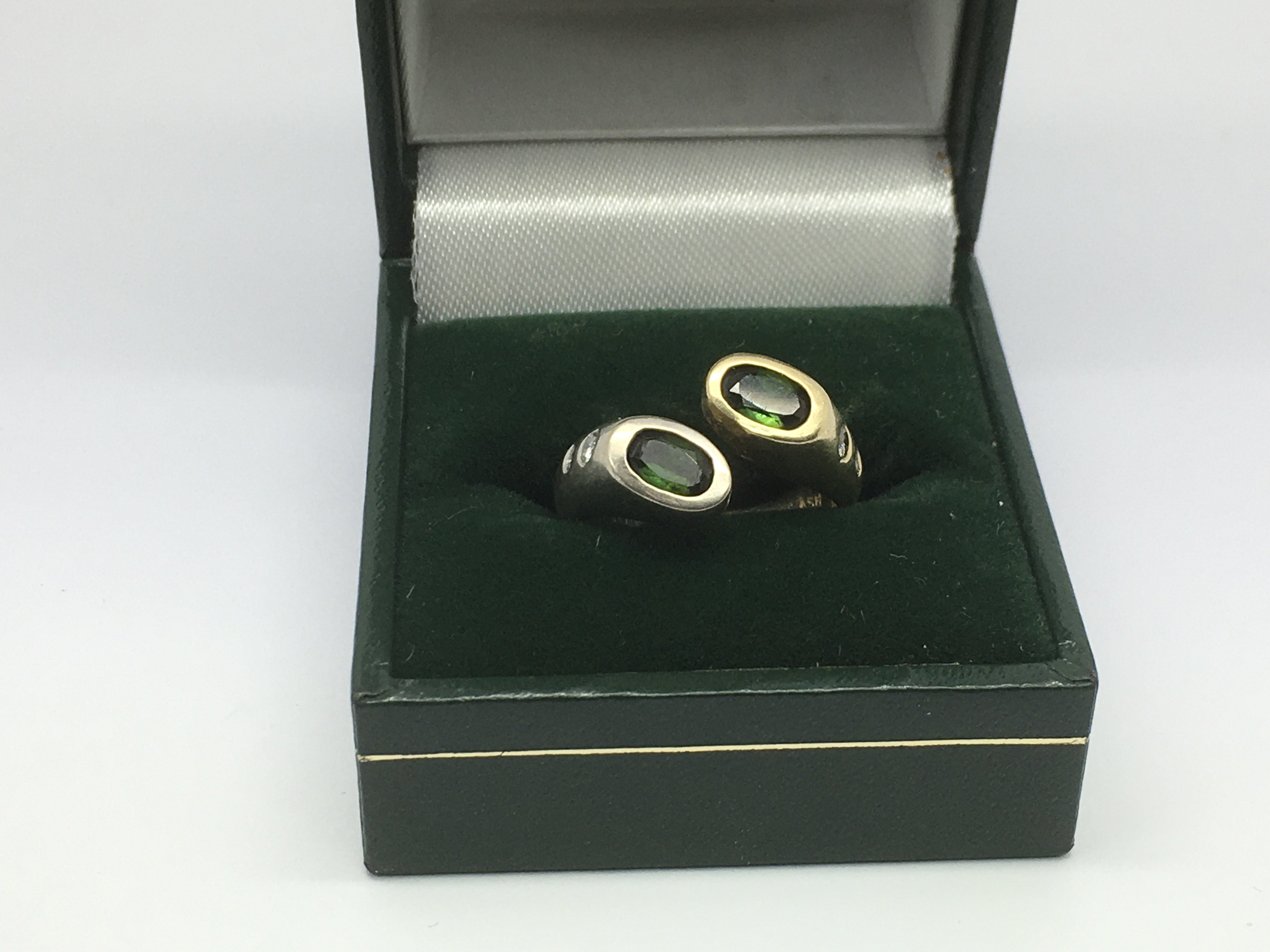 A modern design ring set with two green stones and