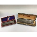 Two cased Hohner harmonicas.