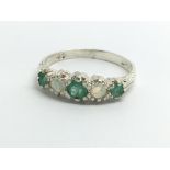 A silver ring set with emeralds and opals