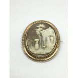 A vintage cameo depicting figures and buildings, a
